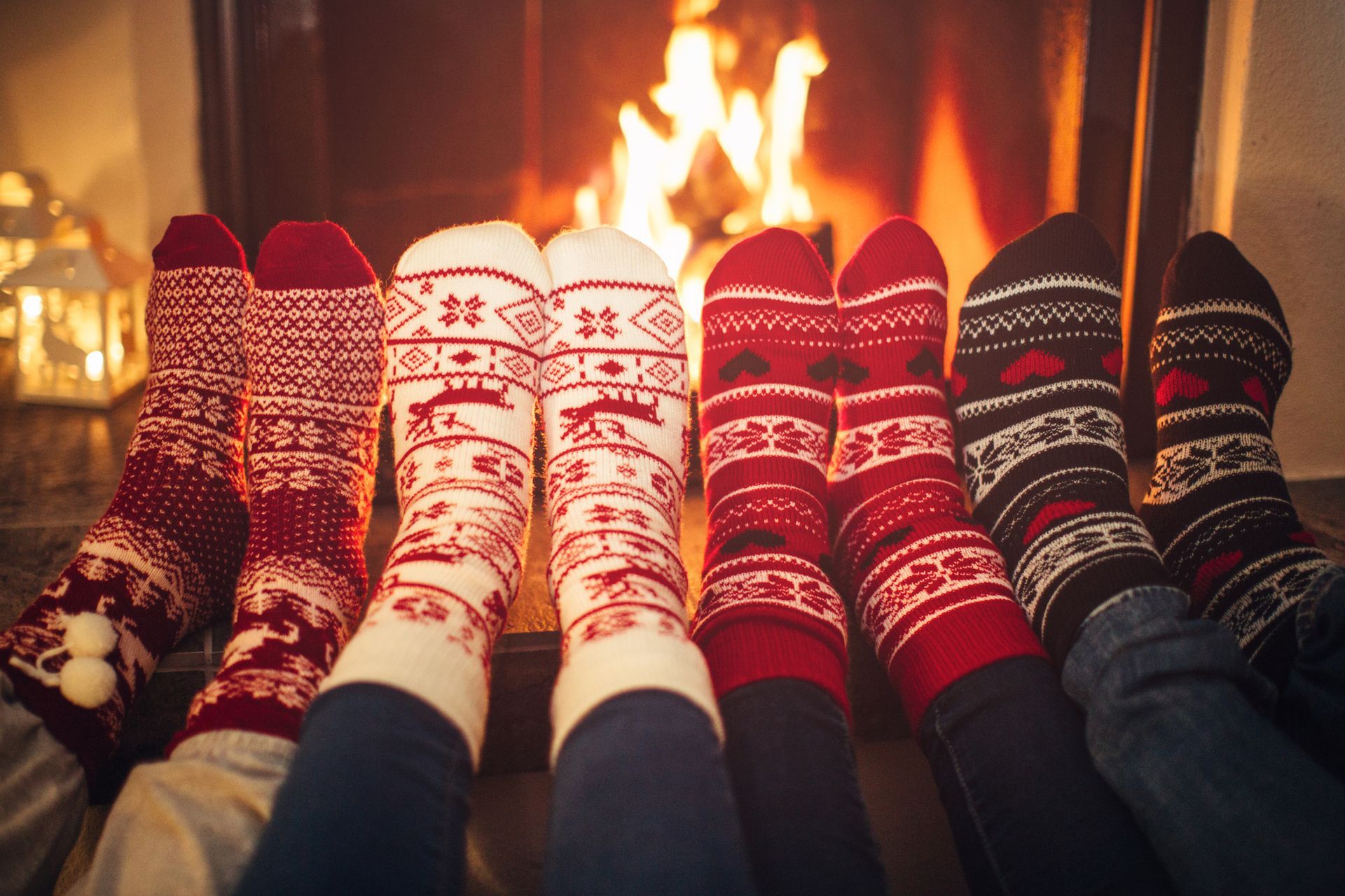 A group of people wearing Christmas socks are sitting on a bed.