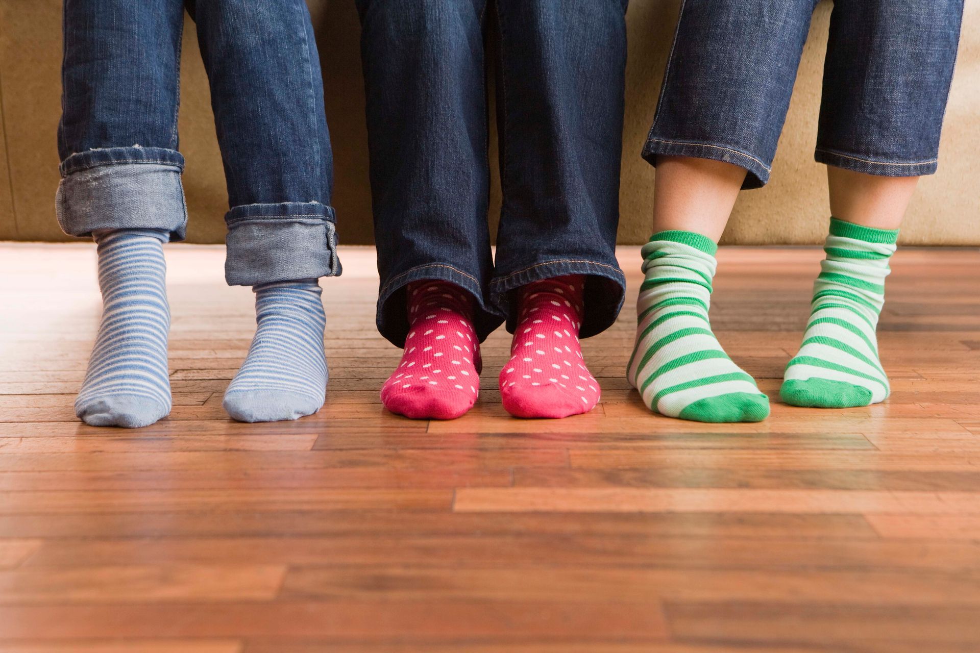 Three people wearing different colored socks are standing next to each other.