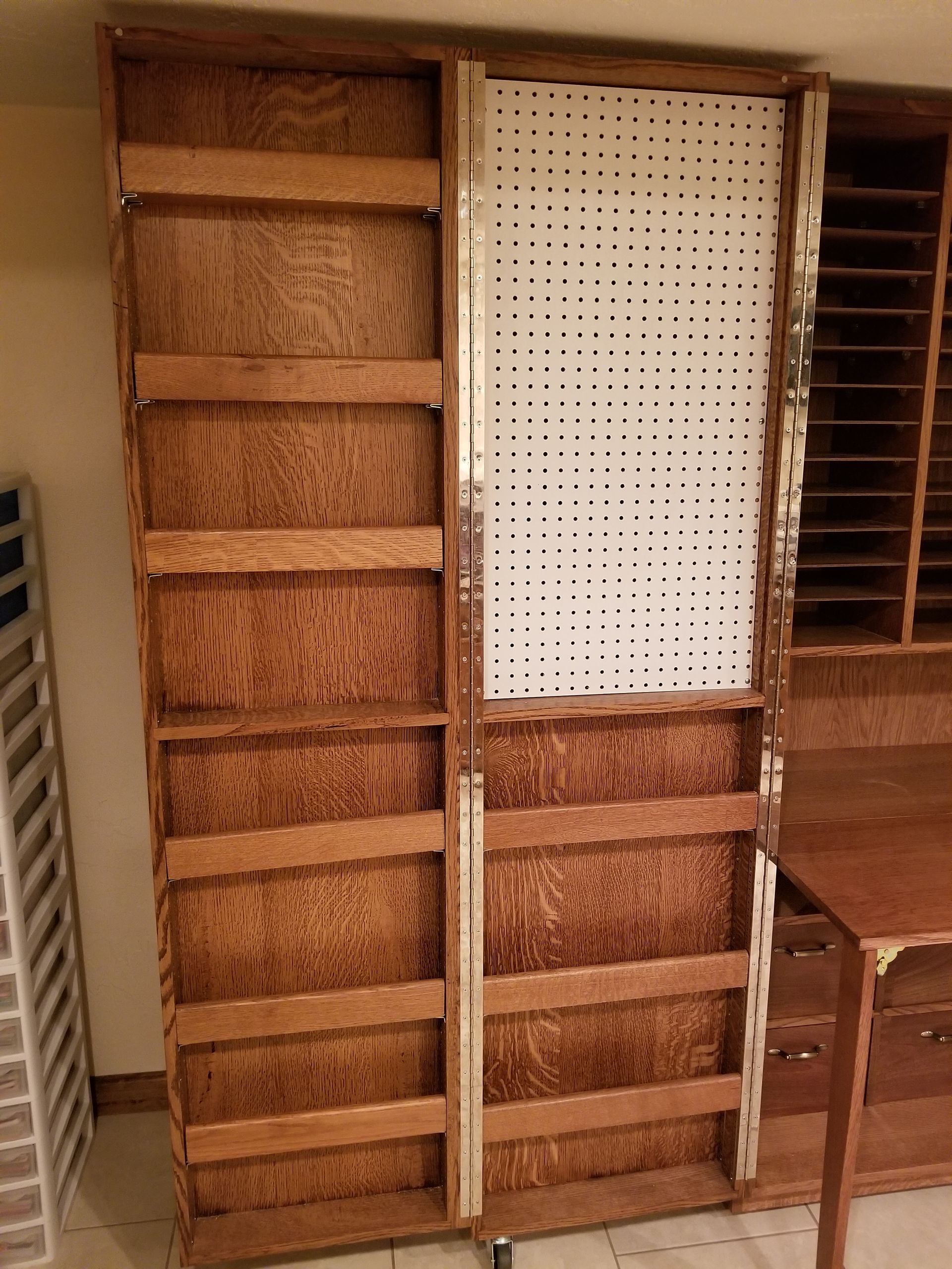 A wooden shelf with holes in it is sitting next to a desk.