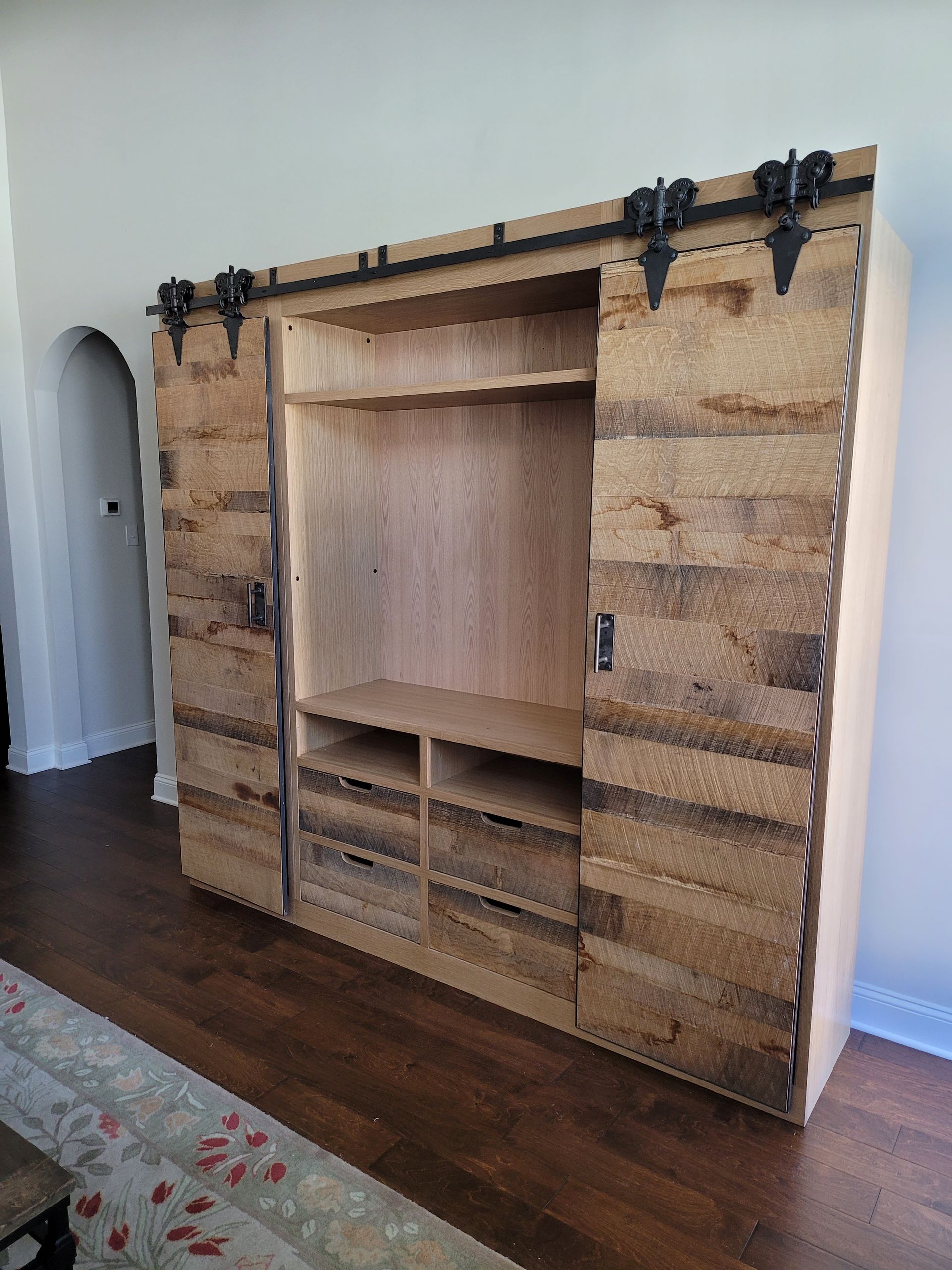 A wooden entertainment center with sliding barn doors in a living room.