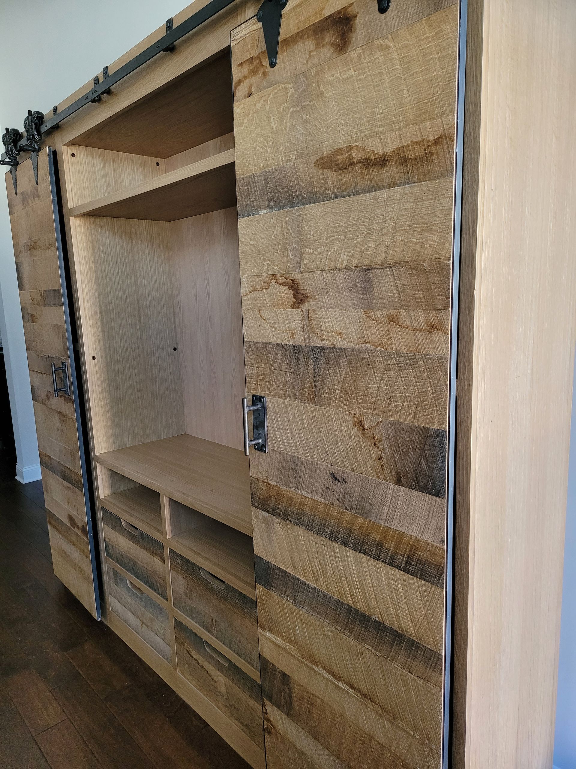 A wooden cabinet with sliding barn doors is sitting on a wooden floor.