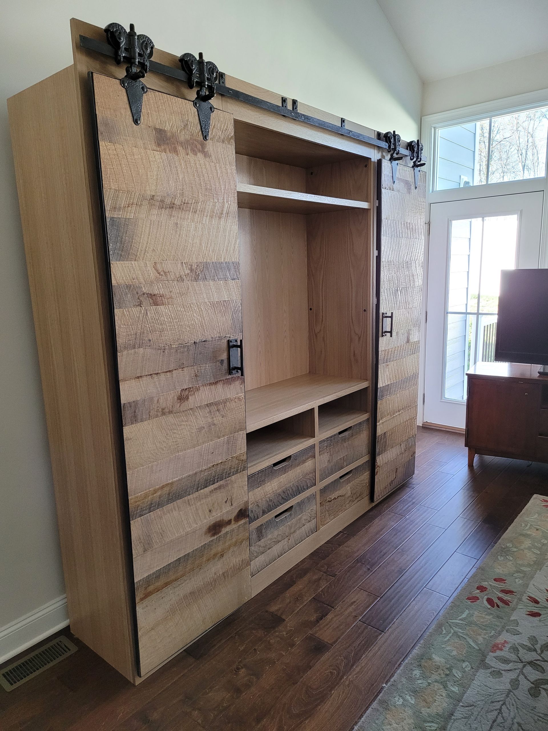 A wooden entertainment center with sliding barn doors in a living room.