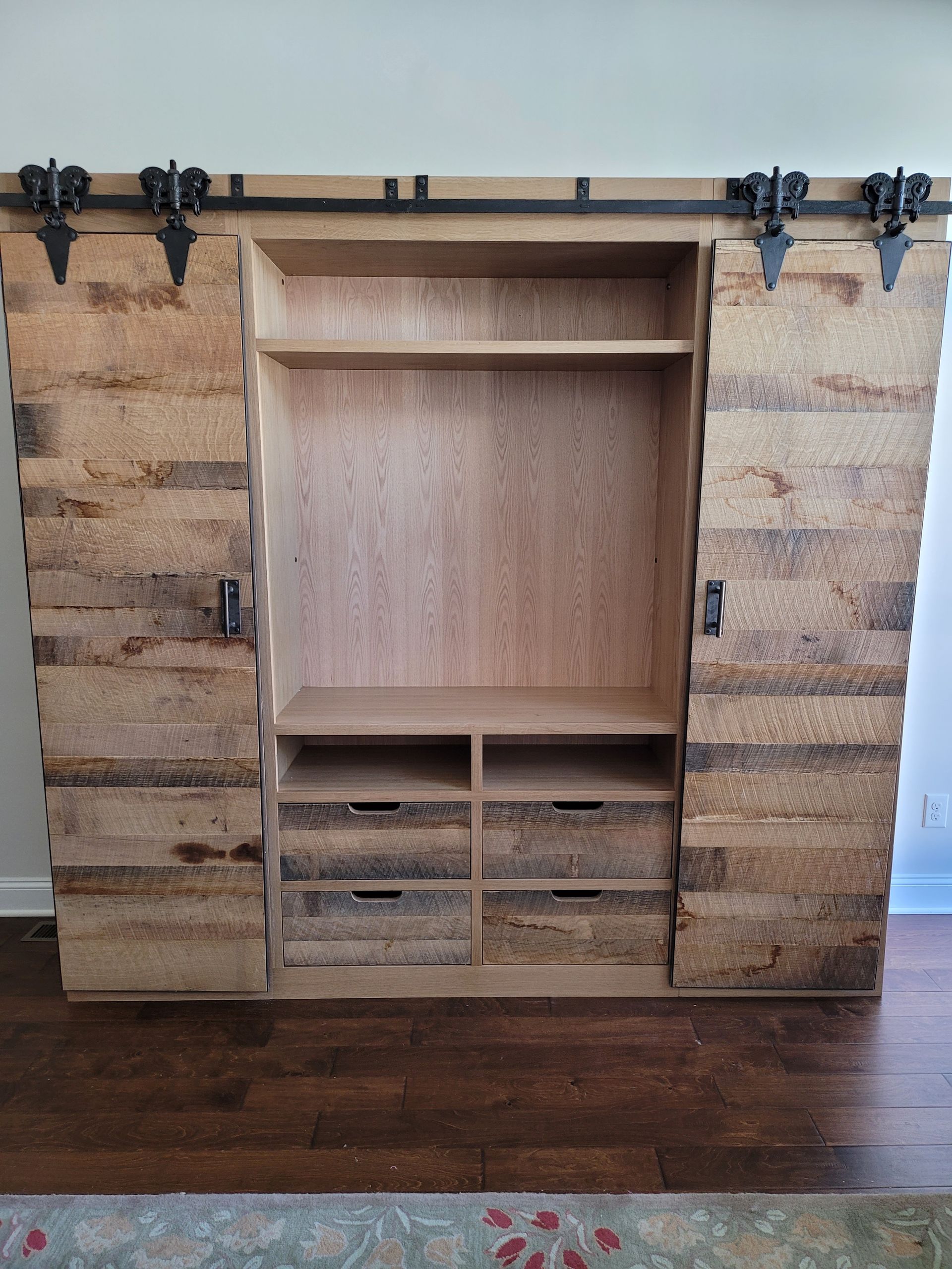 A wooden entertainment center with sliding barn doors in a living room.