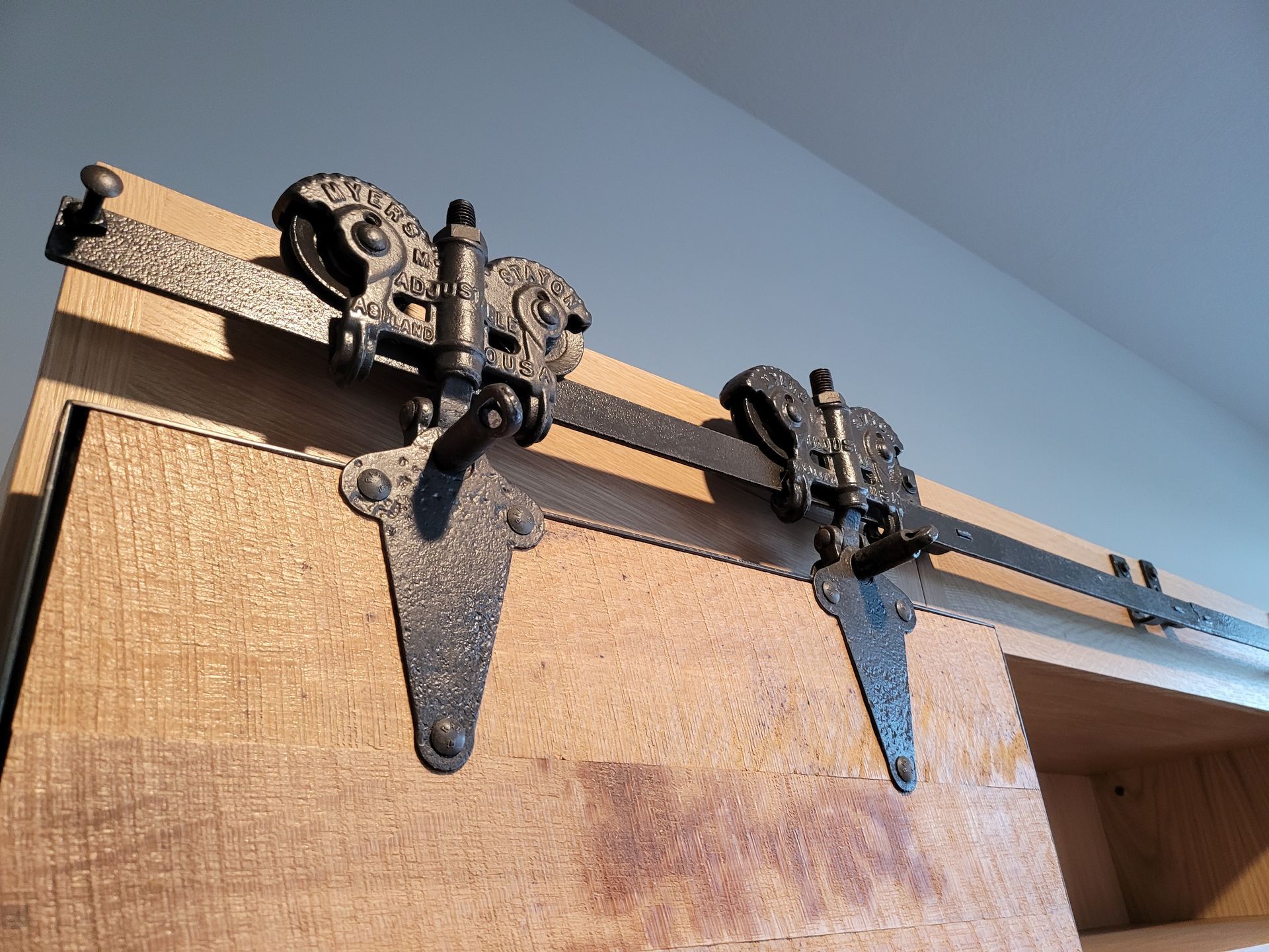 A close up of a sliding barn door hardware on a wooden cabinet
