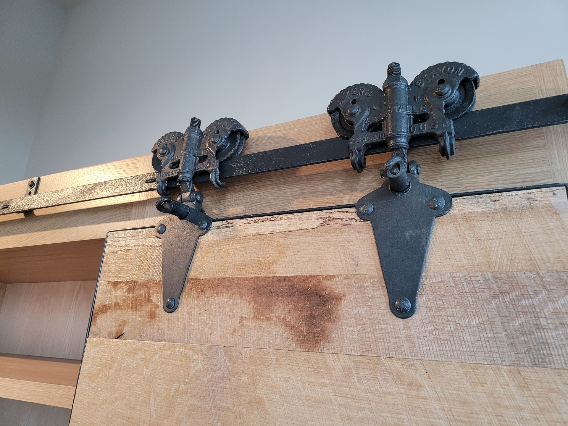 A close up of a sliding barn door hardware on a wooden door.
