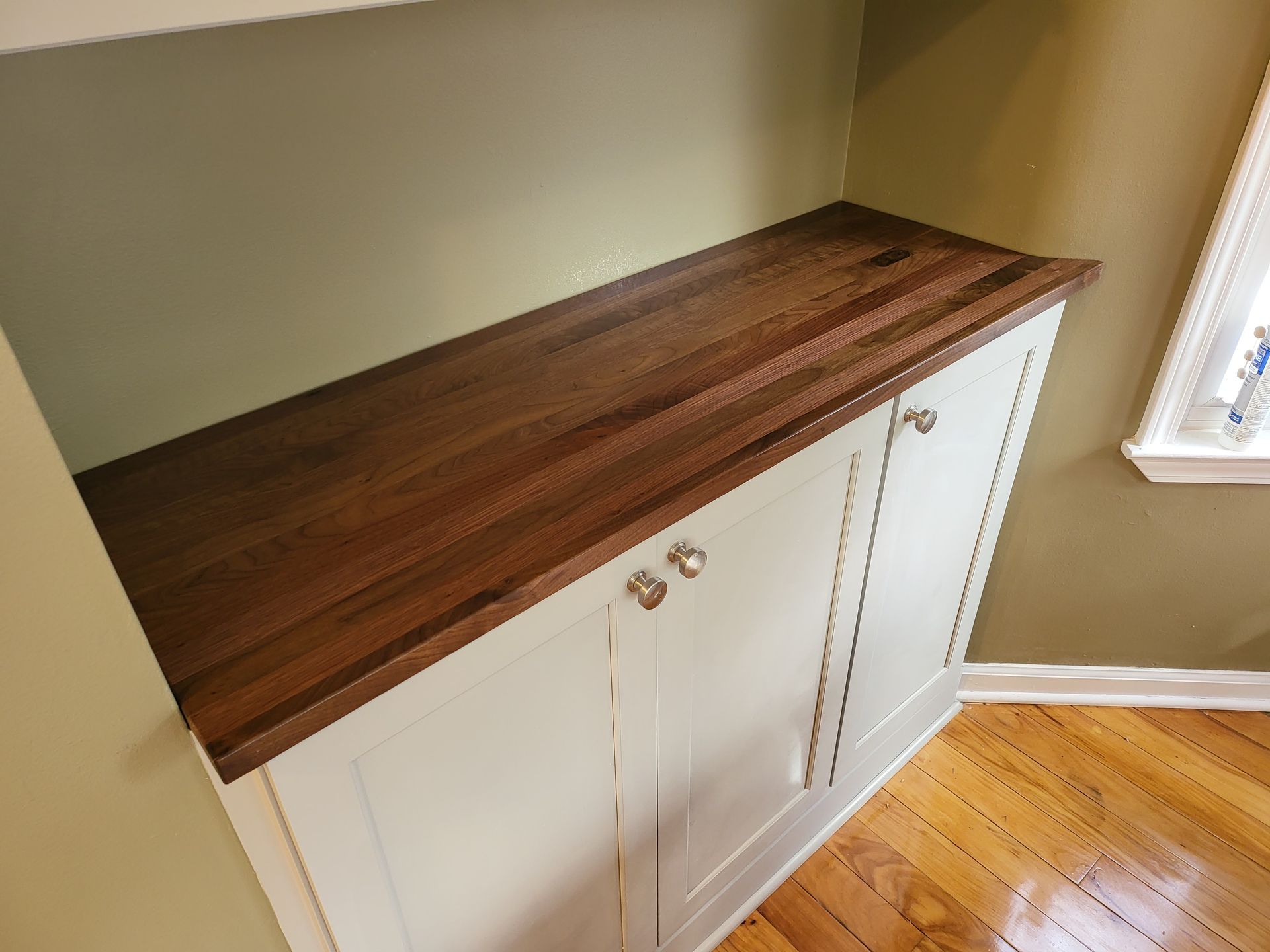 A cabinet with a wooden counter top and white cabinets