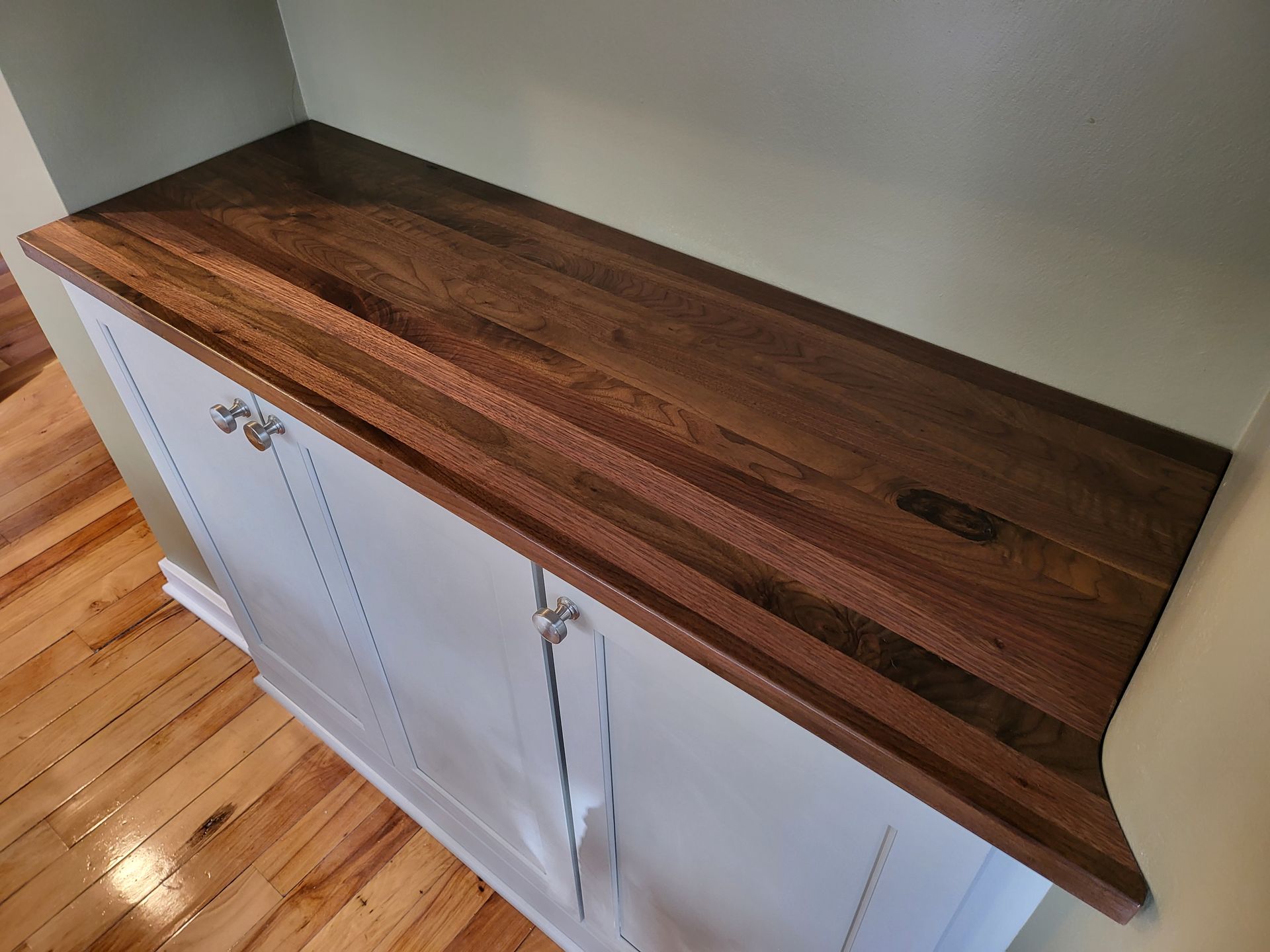 A wooden counter top is sitting on top of a white cabinet.