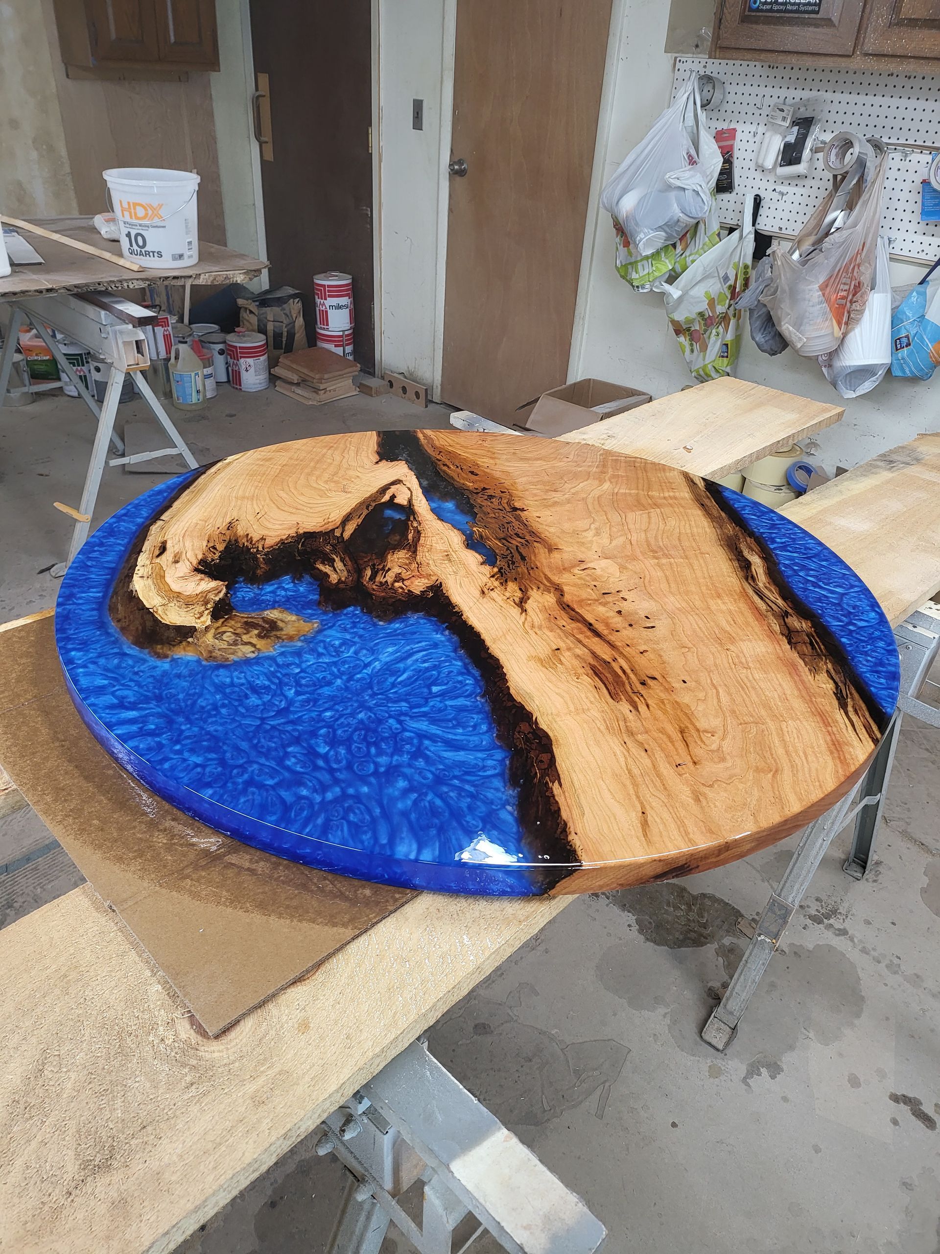 A wooden table with a blue resin coating is sitting on top of a wooden table.