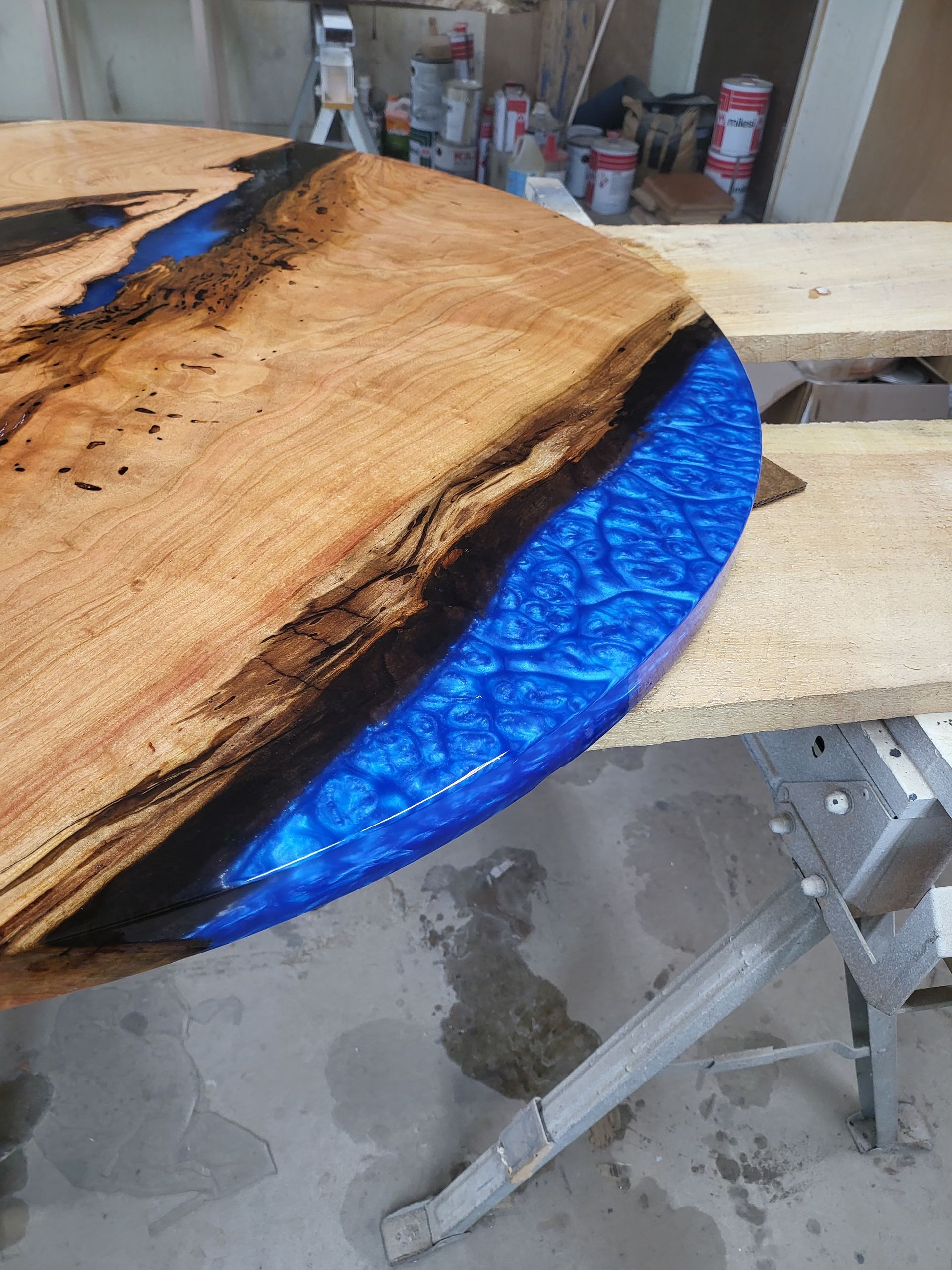 A wooden table with blue resin on it is sitting on a table.