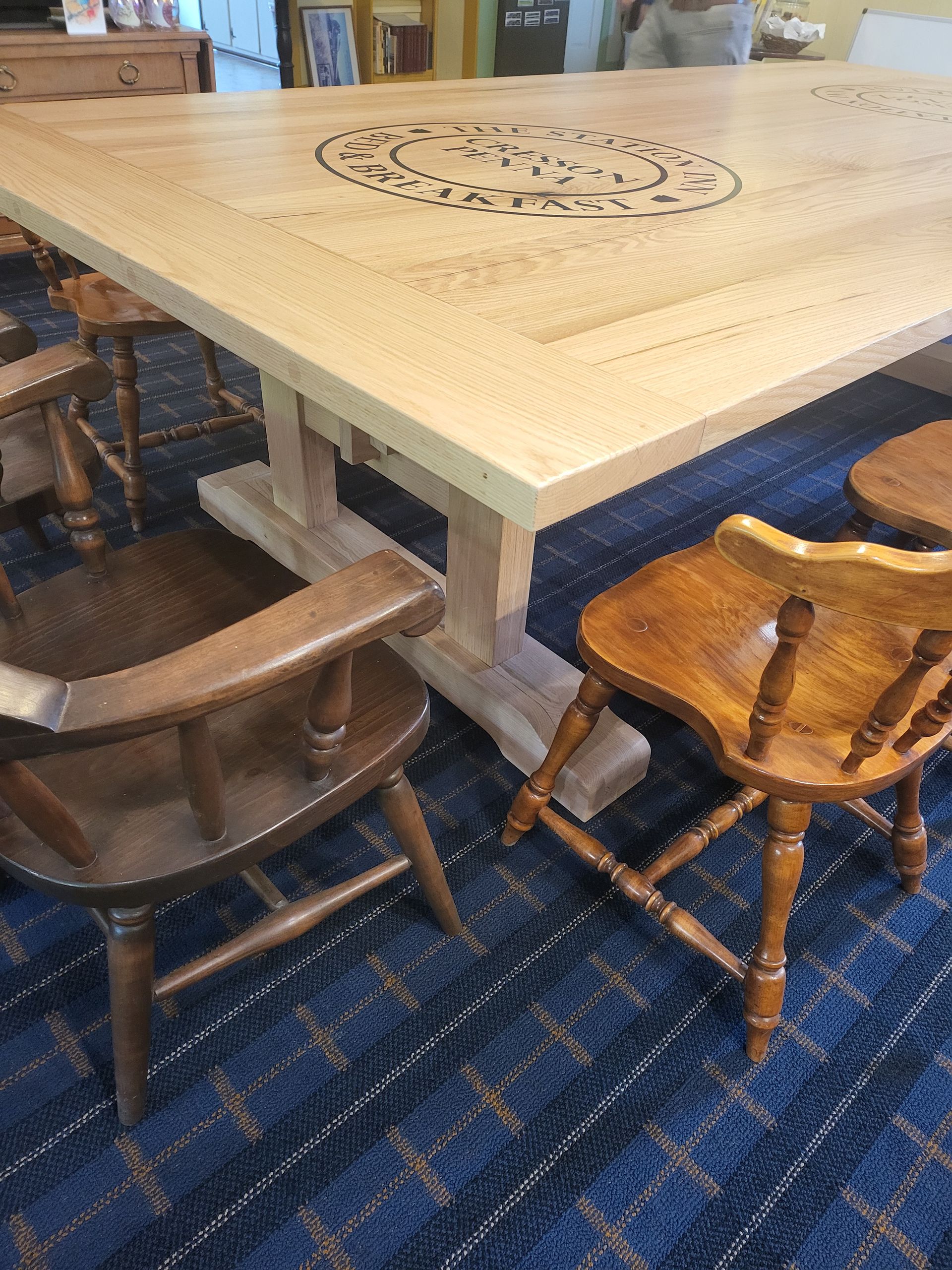 A wooden table and chairs are sitting on a blue carpet.