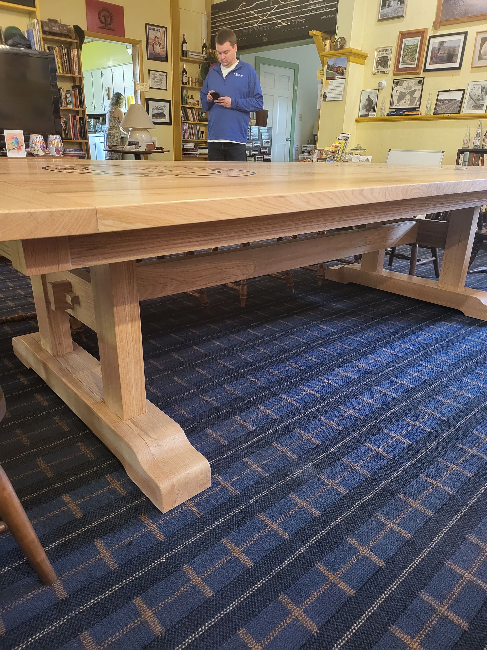 A man is standing in front of a wooden table in a living room.