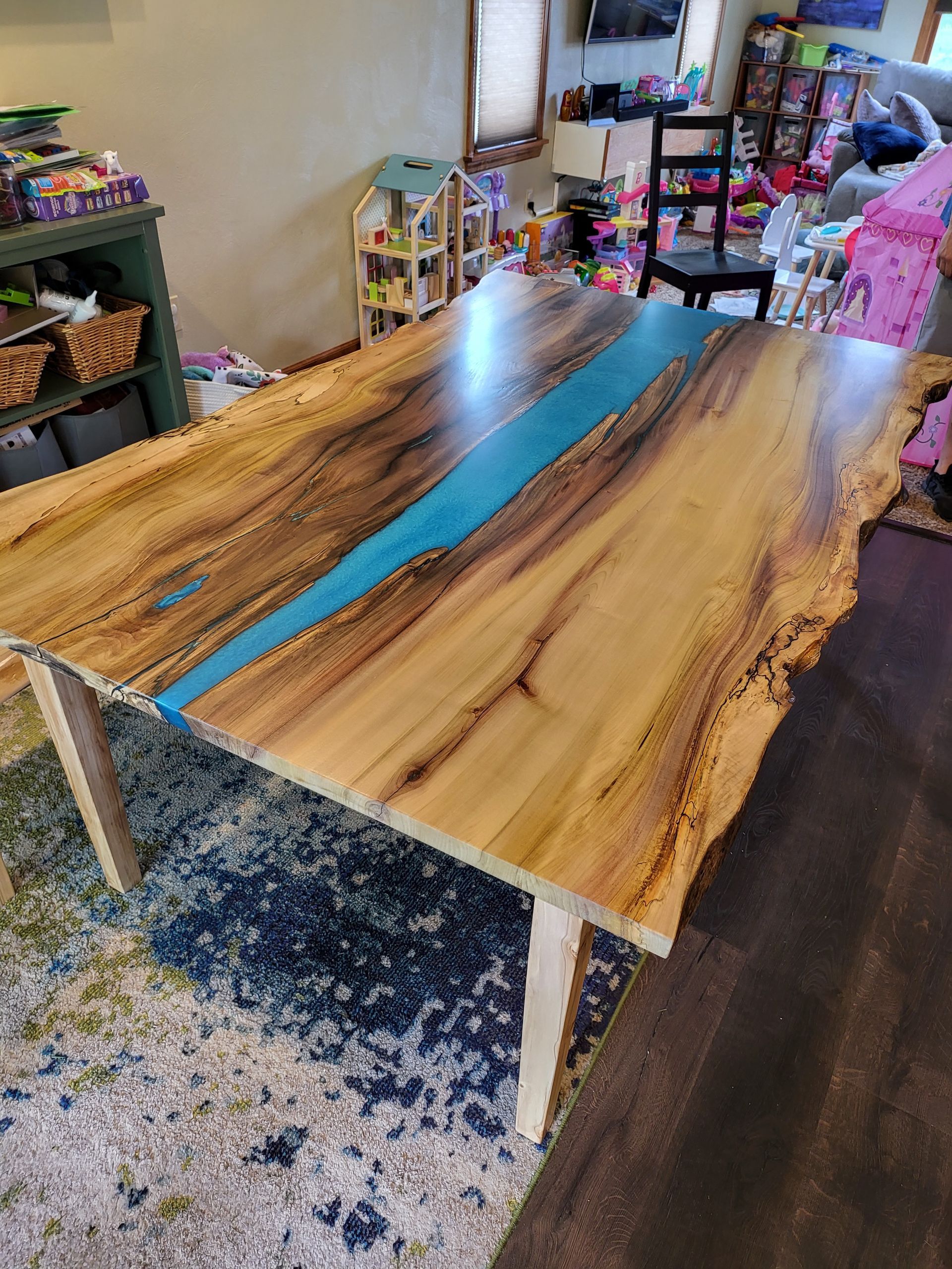 A wooden table with a blue river in the middle is in a living room.