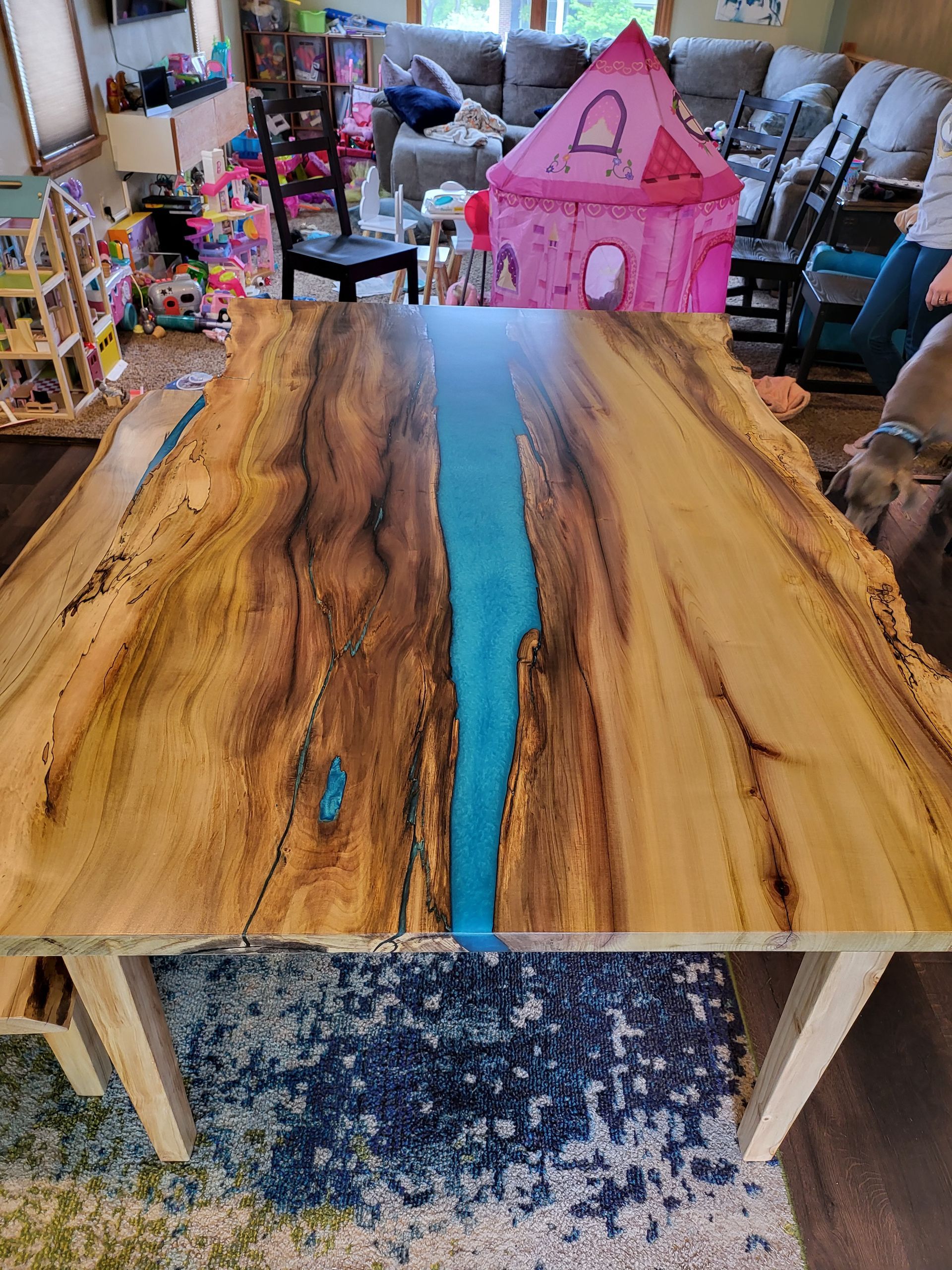 A wooden table with a blue river in the middle of it in a living room.