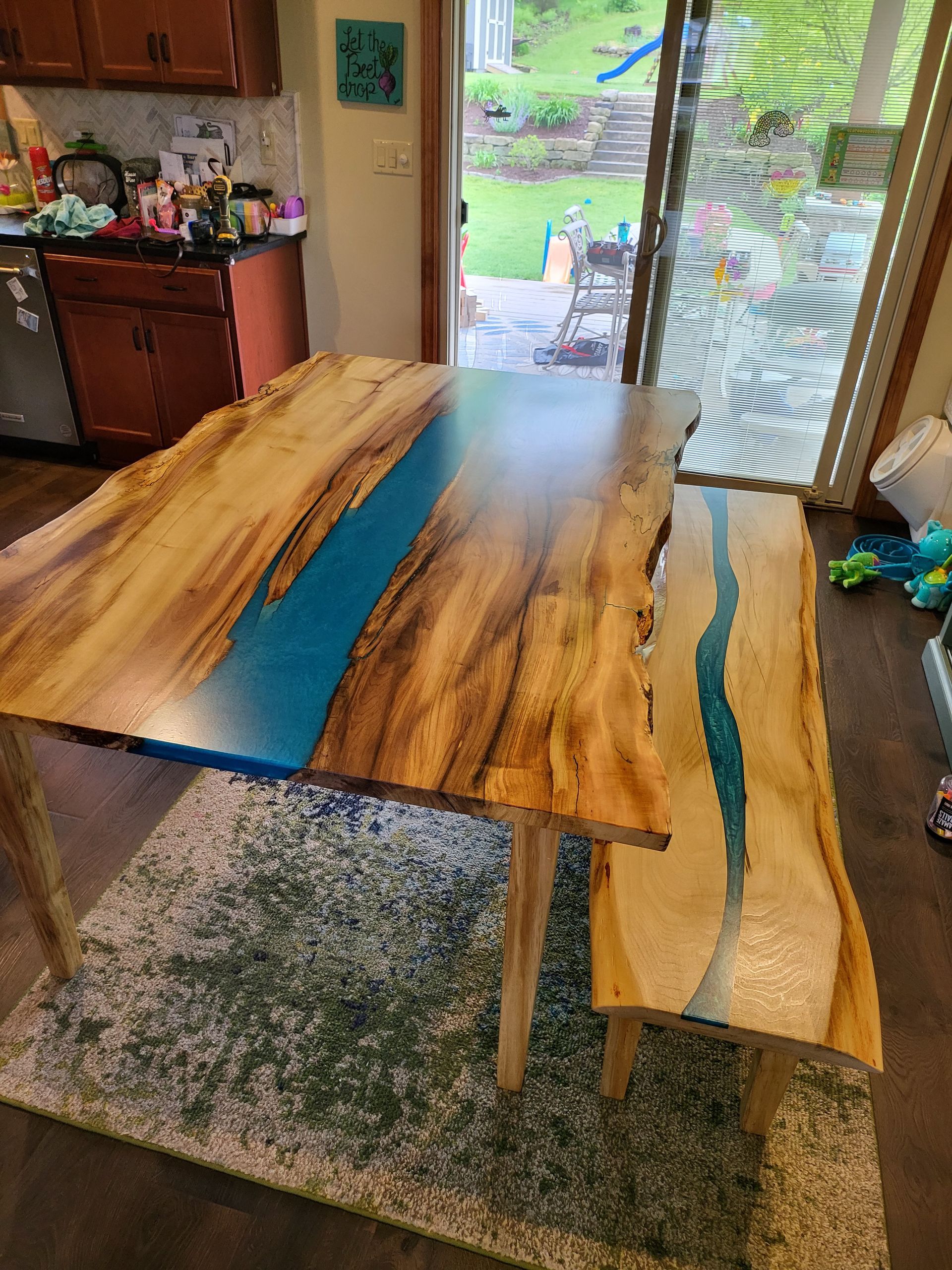 A wooden table with a blue river in the middle of it in a kitchen.