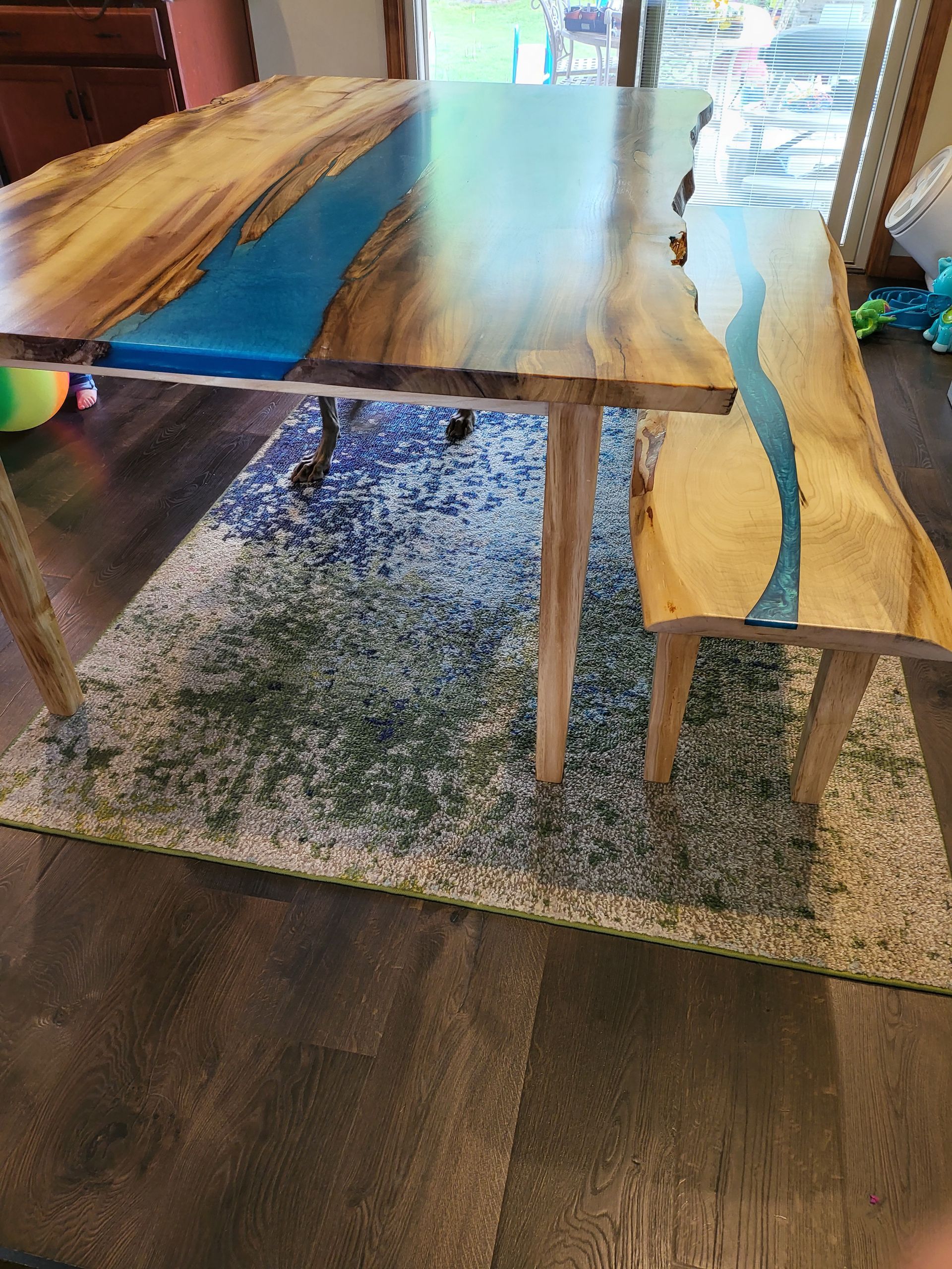 A wooden table and bench are sitting on a rug in a living room.