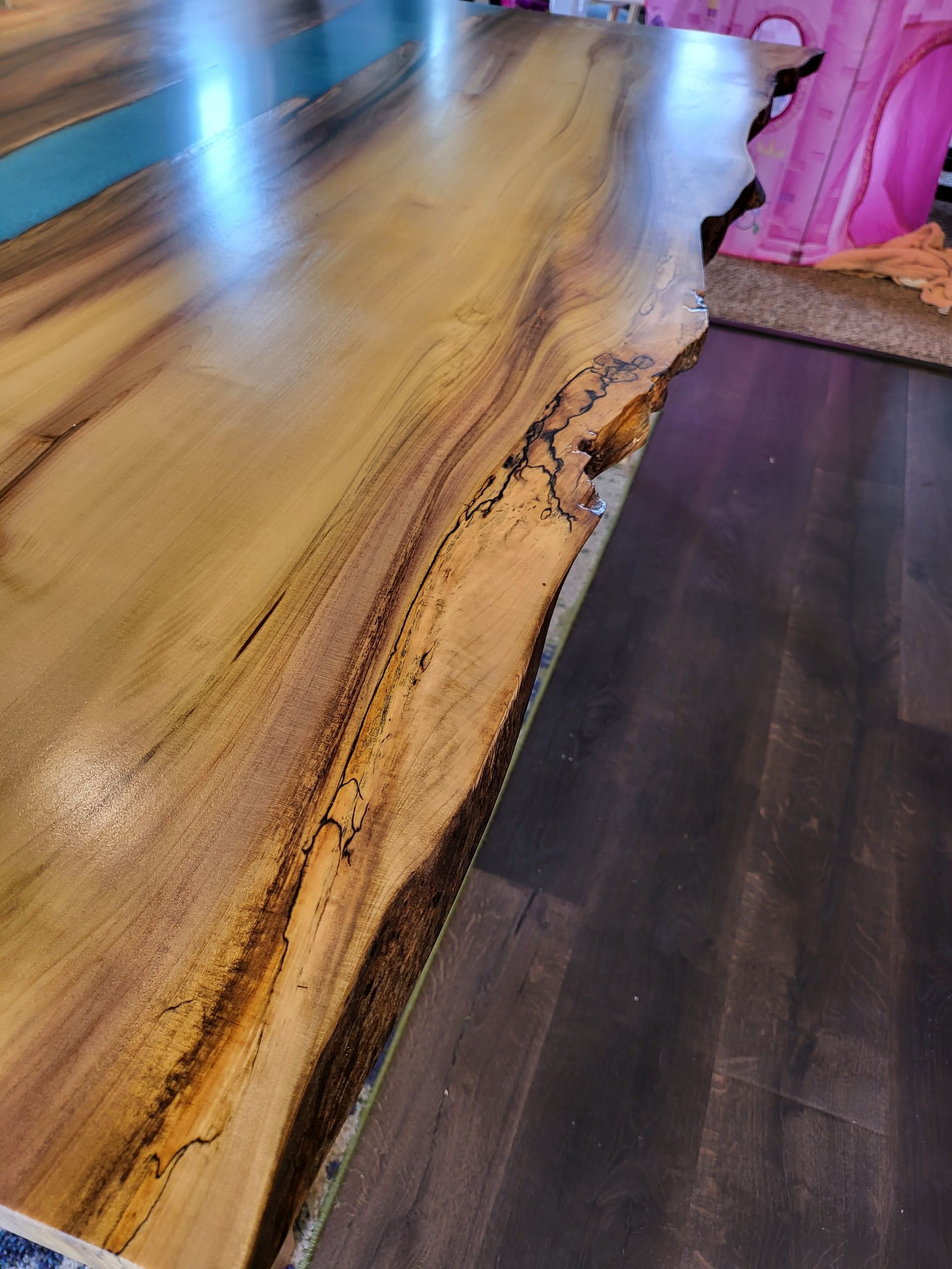 A close up of a wooden table with a wooden floor in a room.