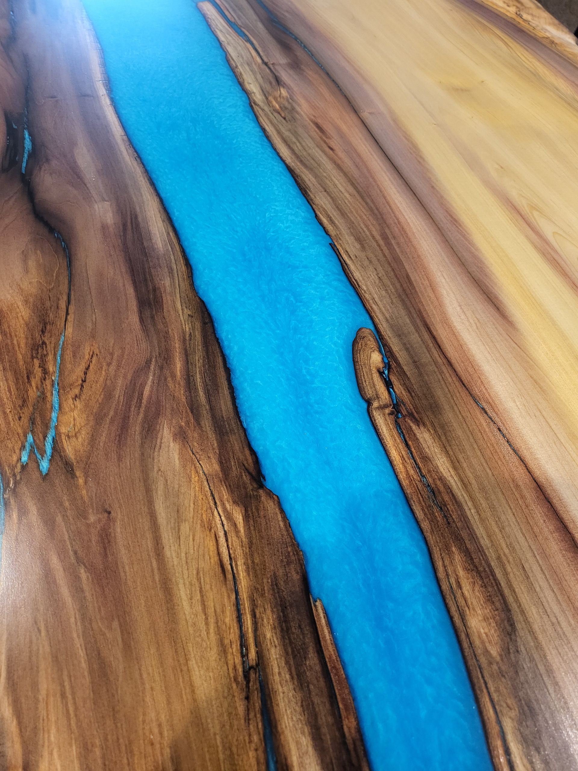 A close up of a wooden table with a blue river running through it.