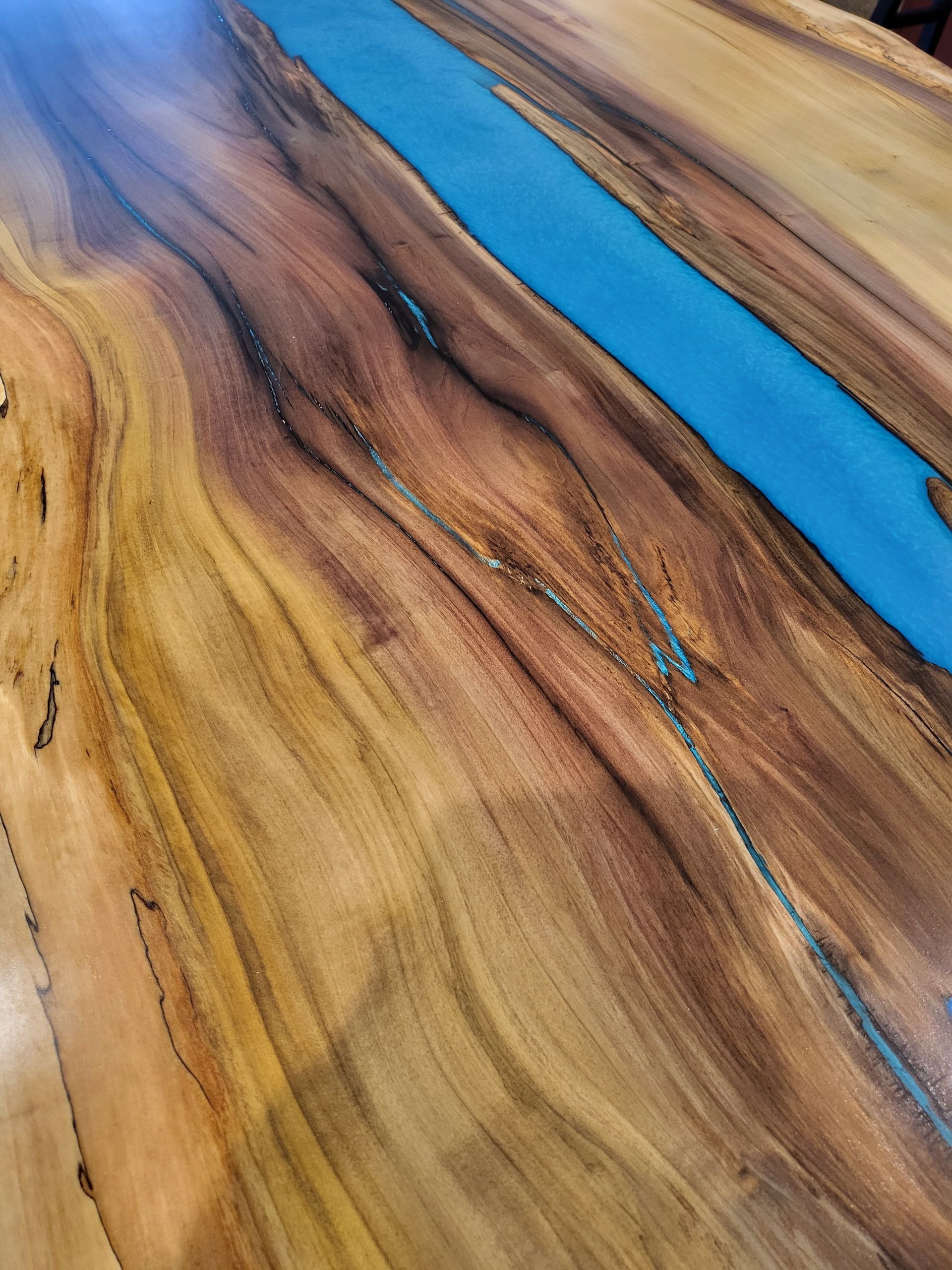 A close up of a wooden table with a blue river running through it.