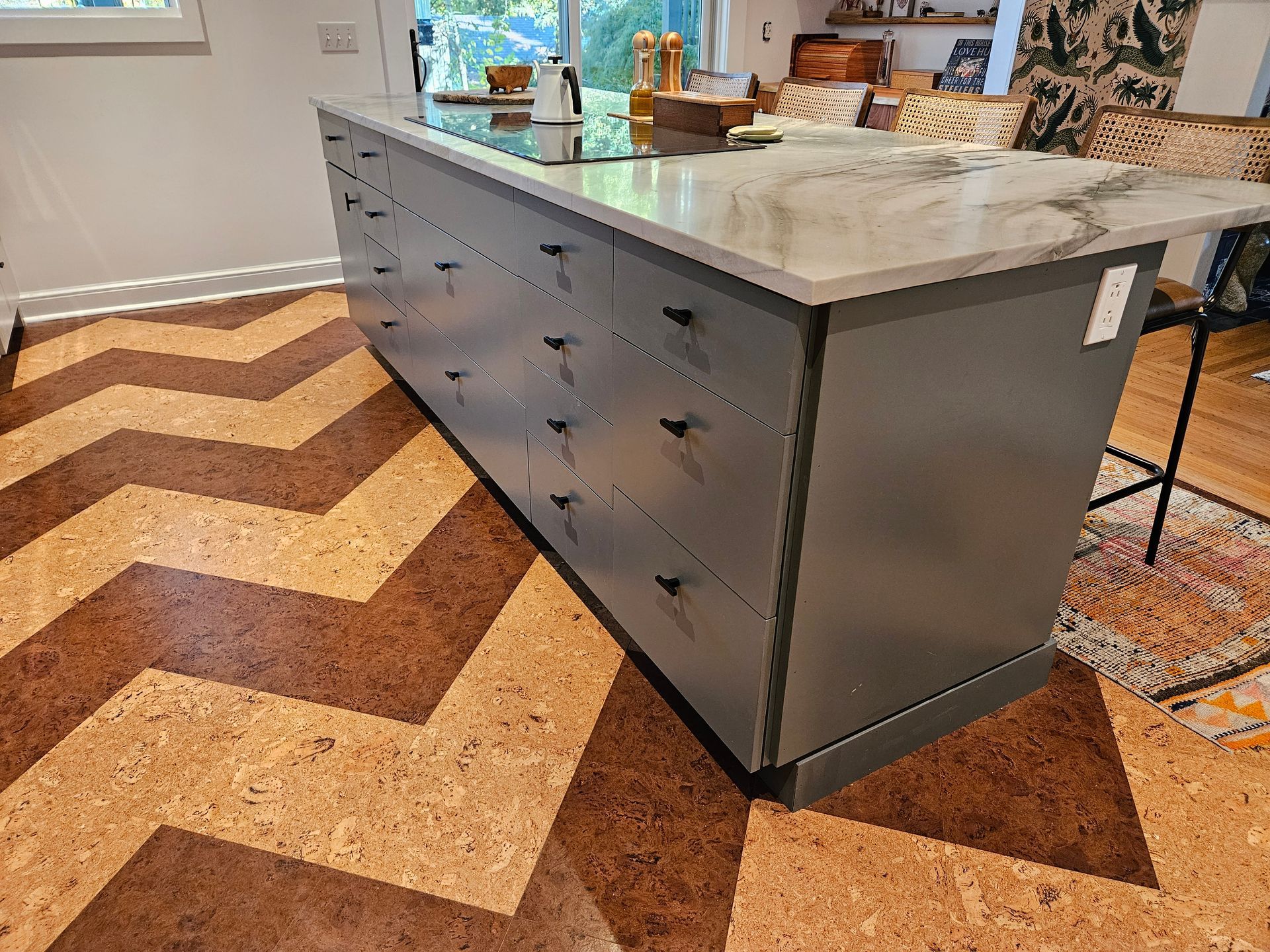 A kitchen with a marble counter top and a cork floor.