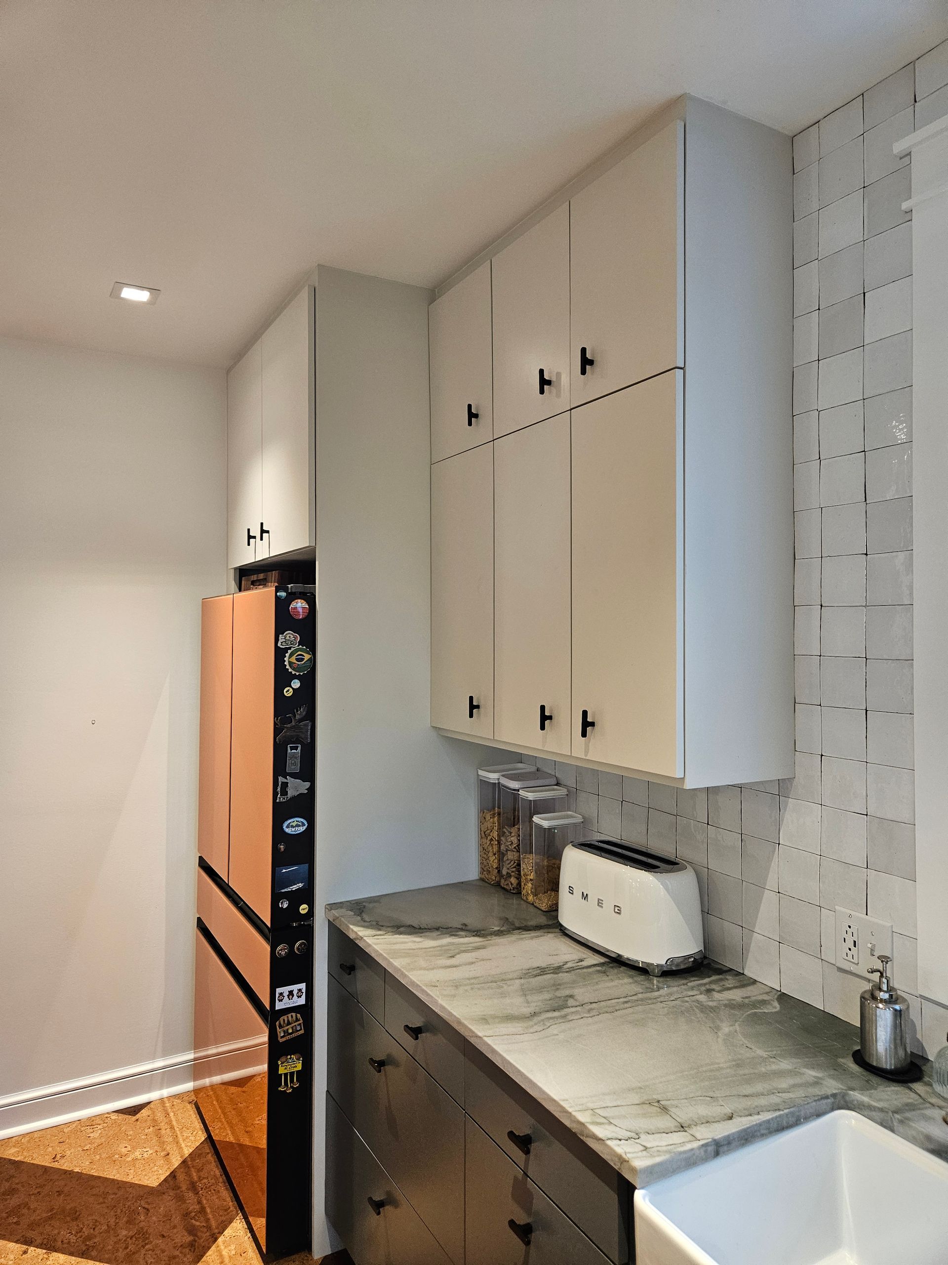 A kitchen with a sink a refrigerator and a toaster