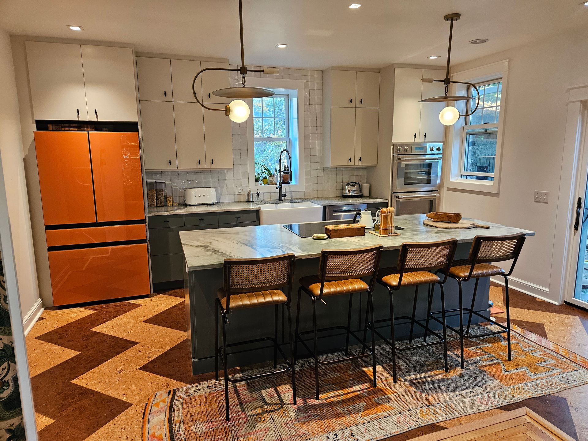 A kitchen with a large island , stools and a refrigerator.