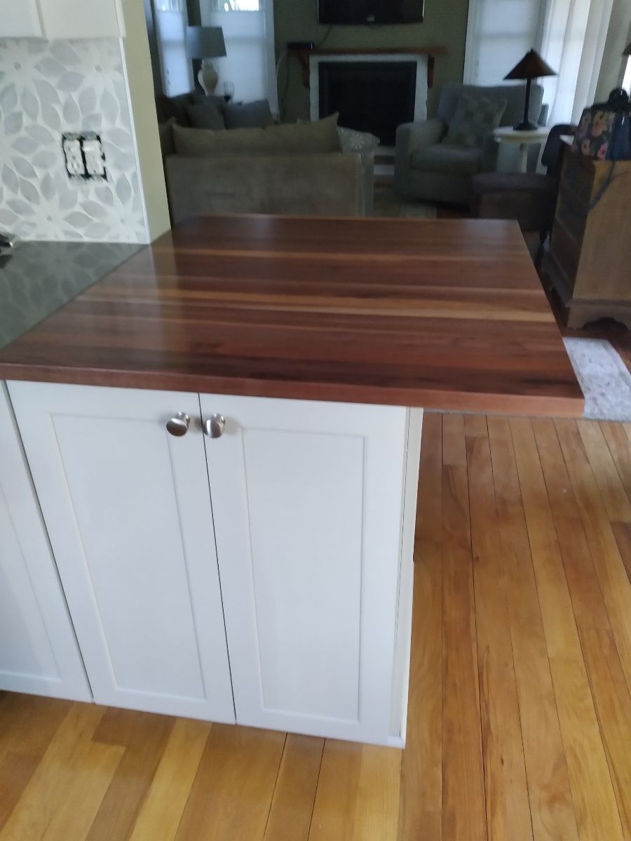 A kitchen island with a wooden top and white cabinets