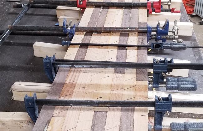 A row of clamps holding a piece of wood