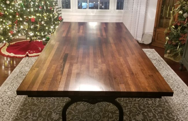A wooden table is sitting on a rug in front of a christmas tree.