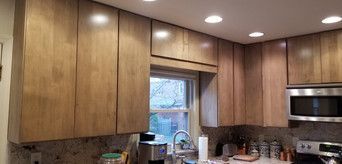 A kitchen with wooden cabinets , stainless steel appliances , and a window.