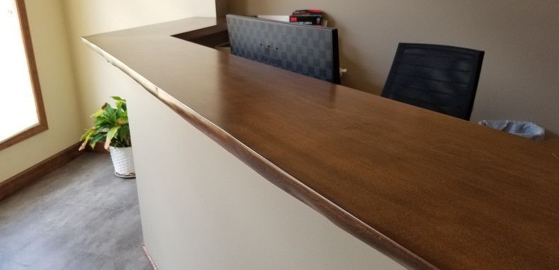 A wooden reception desk with a chair in a room.