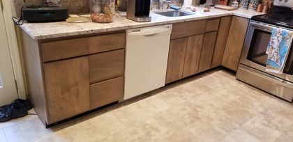 A kitchen with wooden cabinets , stainless steel appliances , a sink , and a dishwasher.