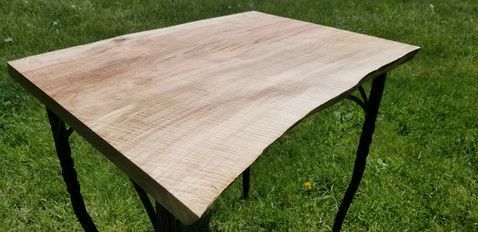 A wooden table is sitting on top of a lush green field.