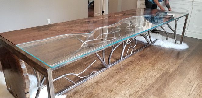 A man is standing next to a table with a glass top in a living room.