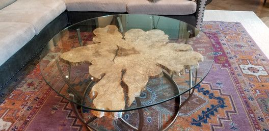 A glass coffee table with a piece of wood on top of it in a living room.