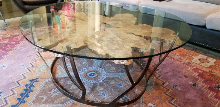 A glass coffee table is sitting on top of a rug in a living room.