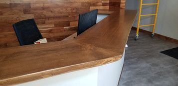 A wooden reception desk with two chairs in a room with a wooden wall.
