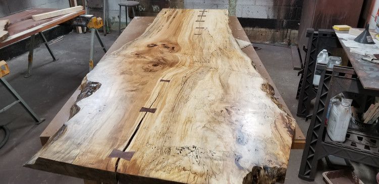 A large piece of wood is sitting on top of a wooden table in a workshop.