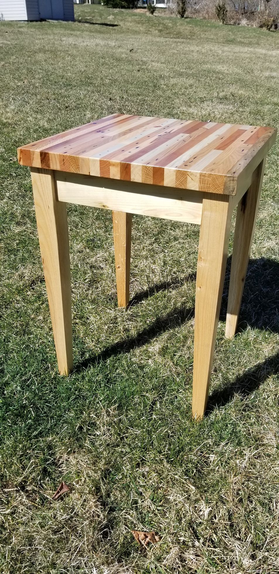 A small wooden table is sitting on top of a lush green field.