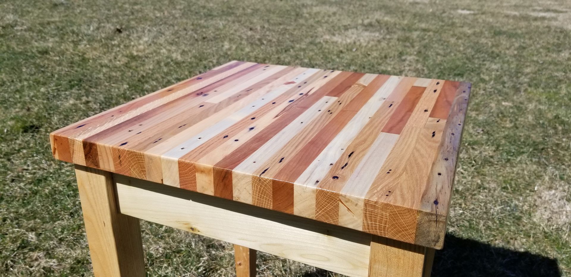 A wooden table is sitting on top of a grassy field.