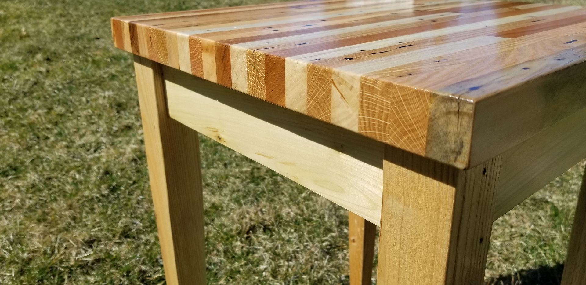 A wooden table is sitting on top of a lush green field.