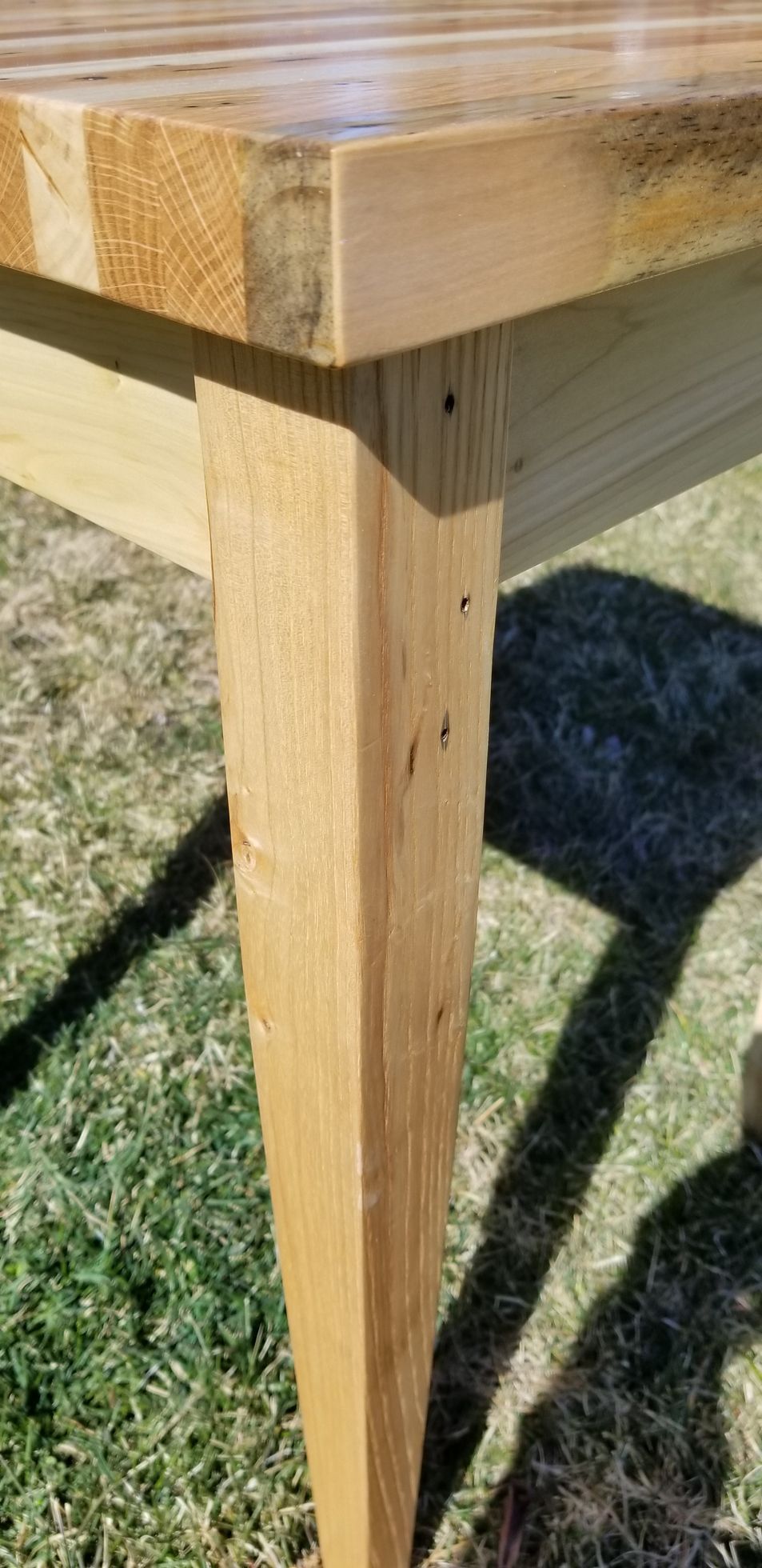 A wooden table is sitting on top of a lush green field.