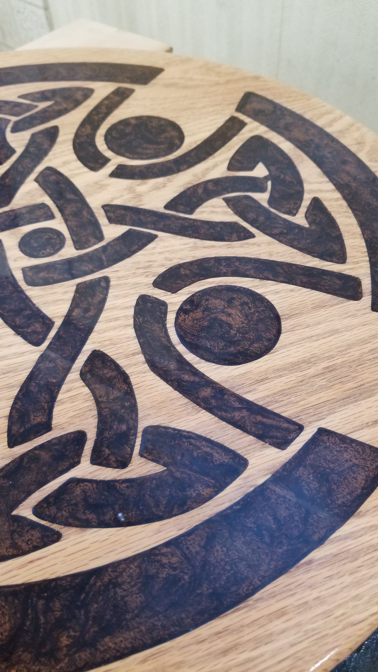 A close up of a wooden table with a celtic design on it.