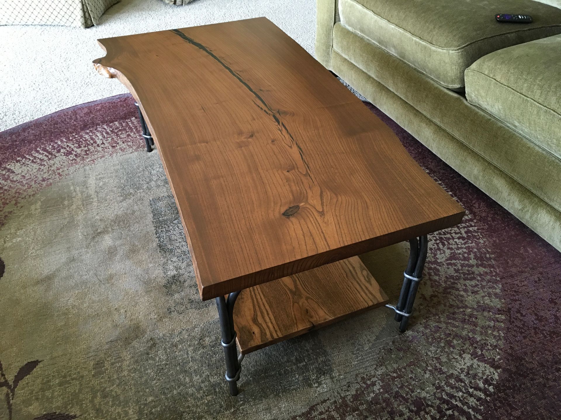 A wooden coffee table is in a living room next to a couch.