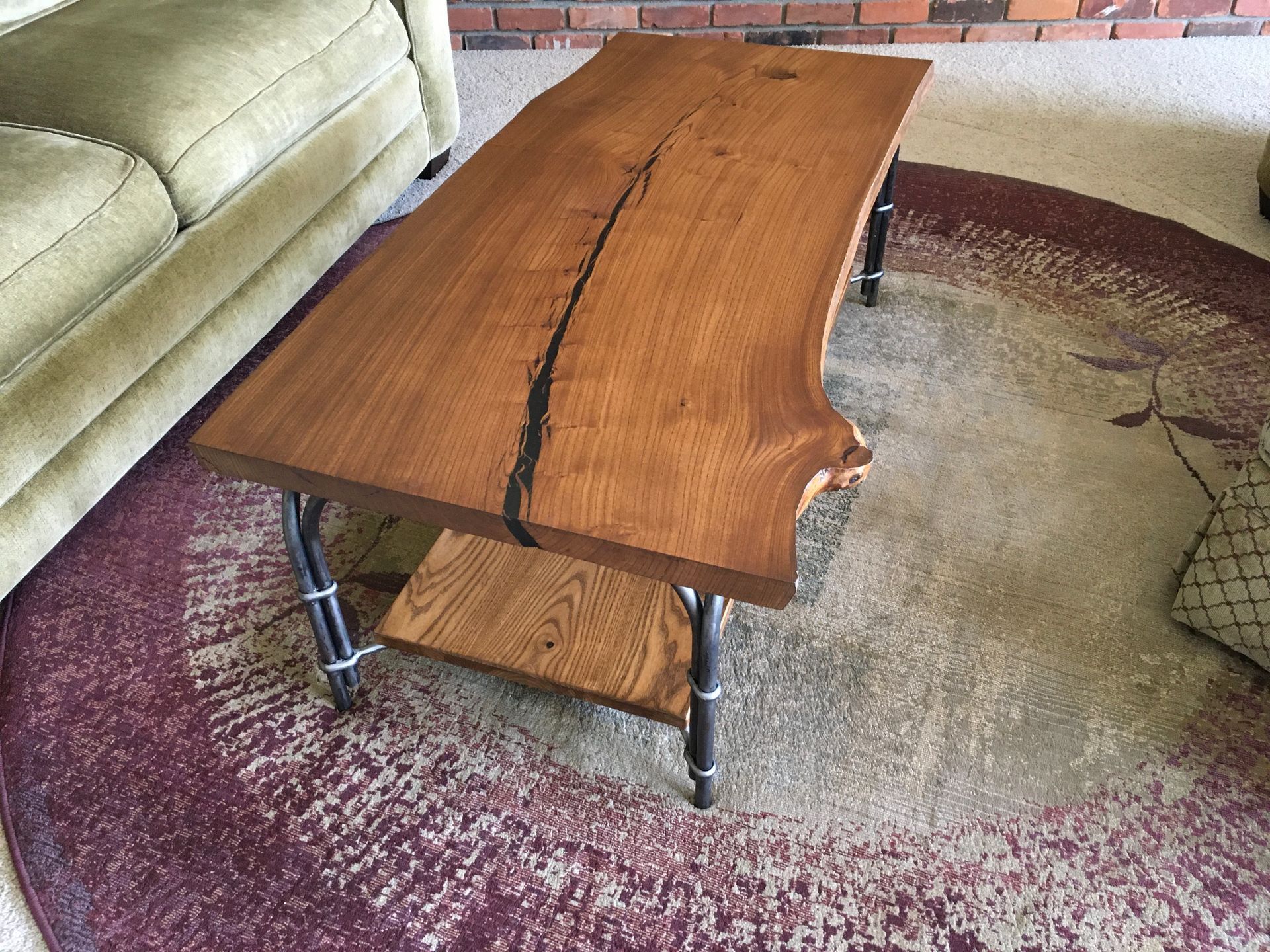 A wooden coffee table is sitting on a rug in a living room next to a couch.