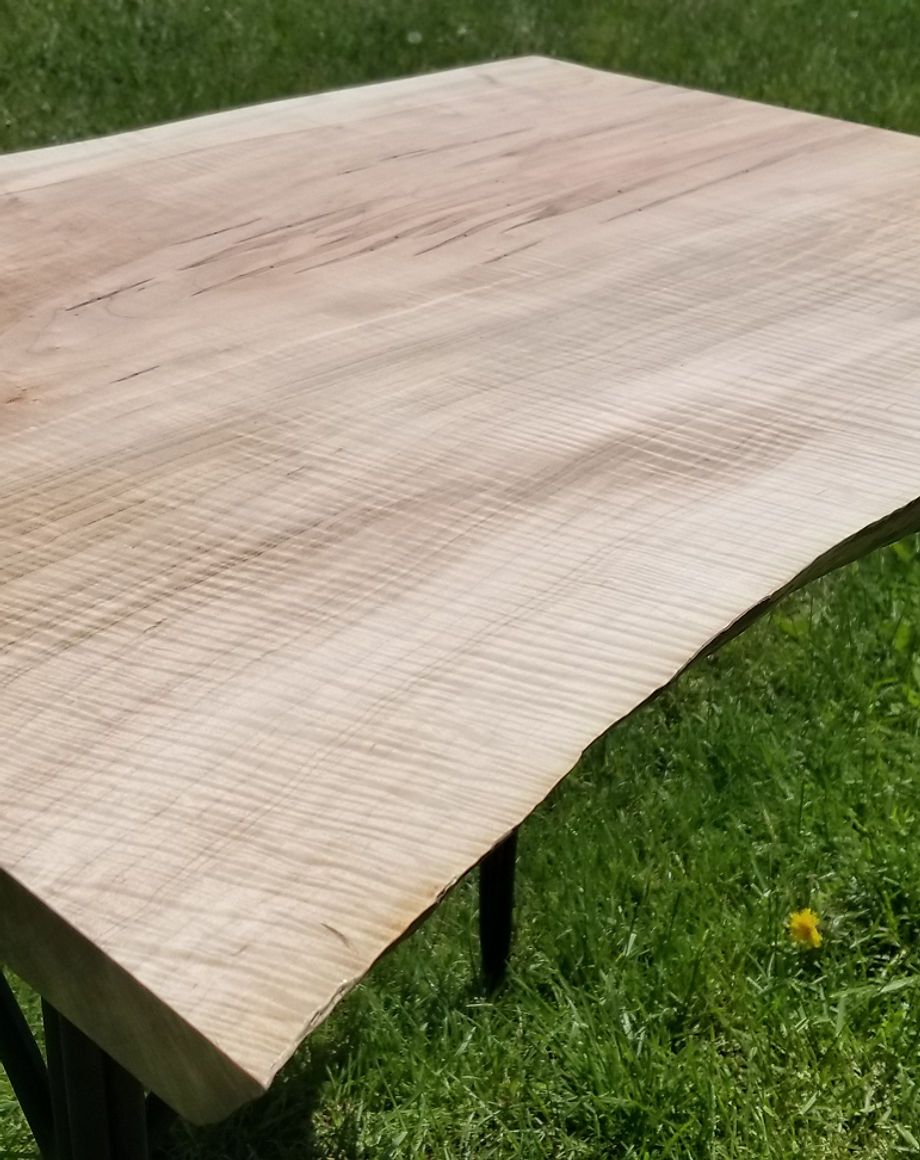 A wooden table is sitting on top of a lush green field.