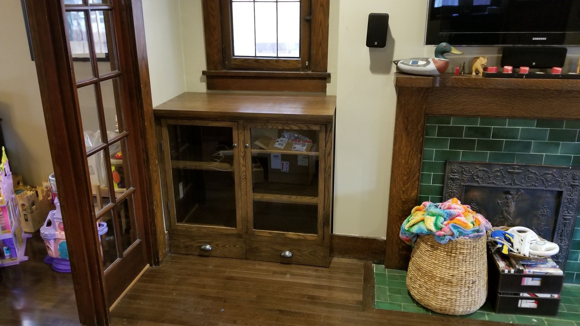 A living room with a fireplace , a dresser , and a television.