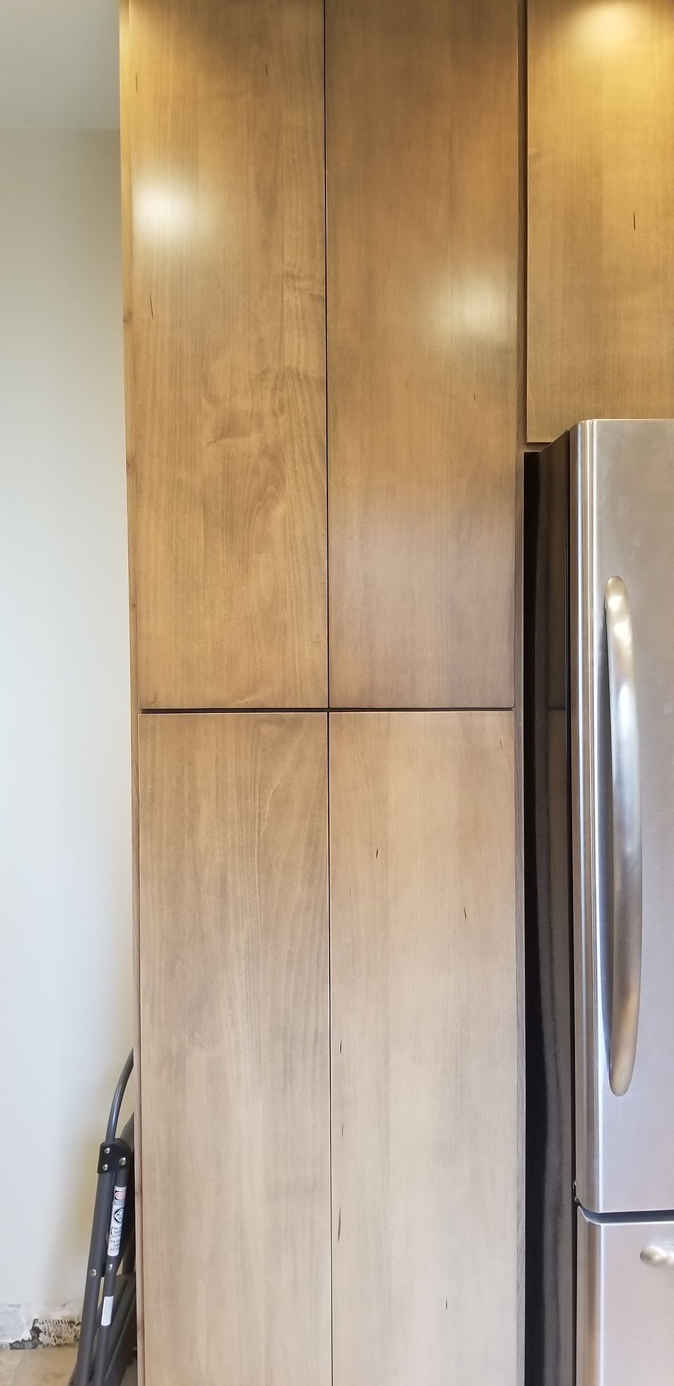A stainless steel refrigerator is sitting next to a wooden cabinet in a kitchen.
