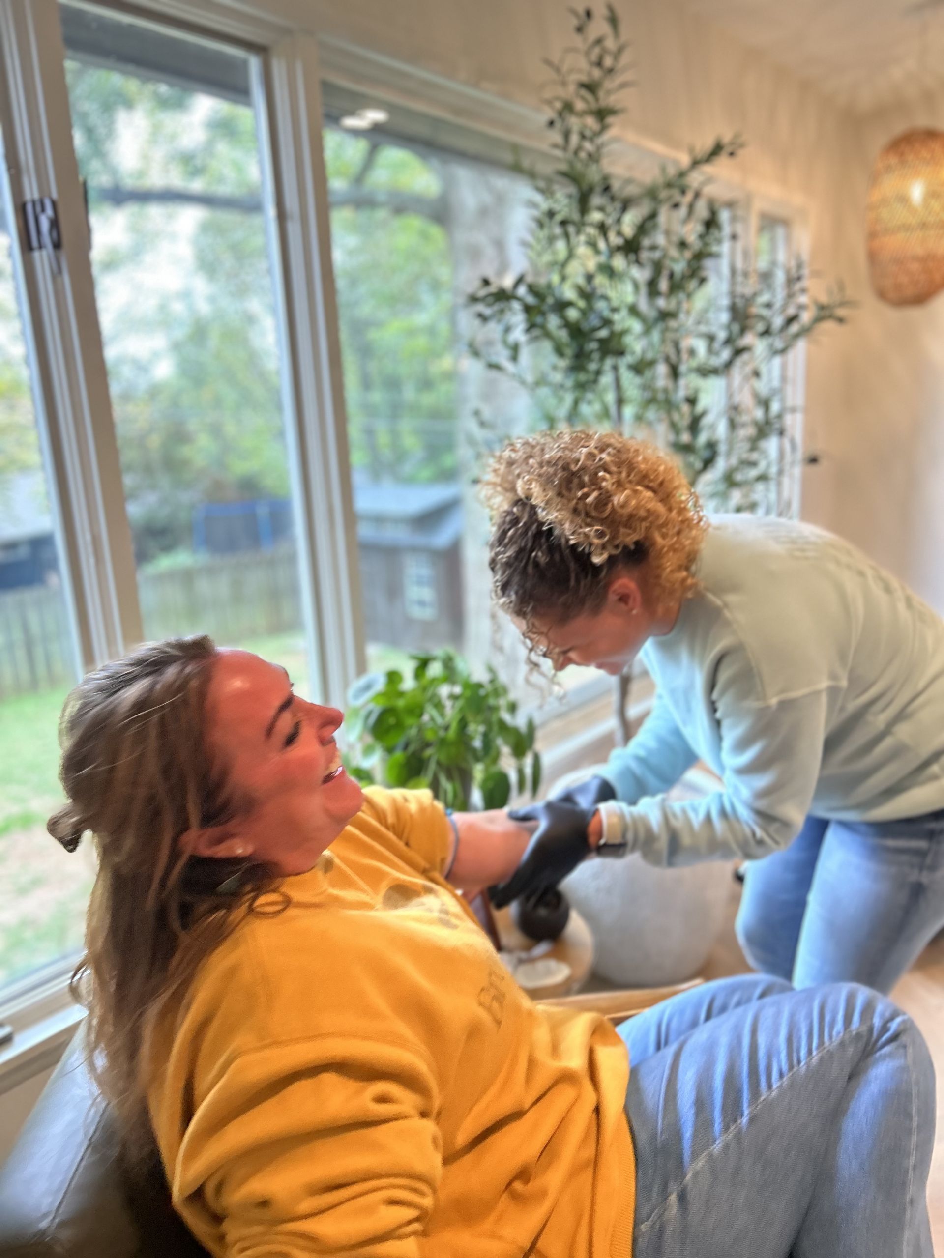 Person getting an IV in a sunlit room; another person is drawing blood.