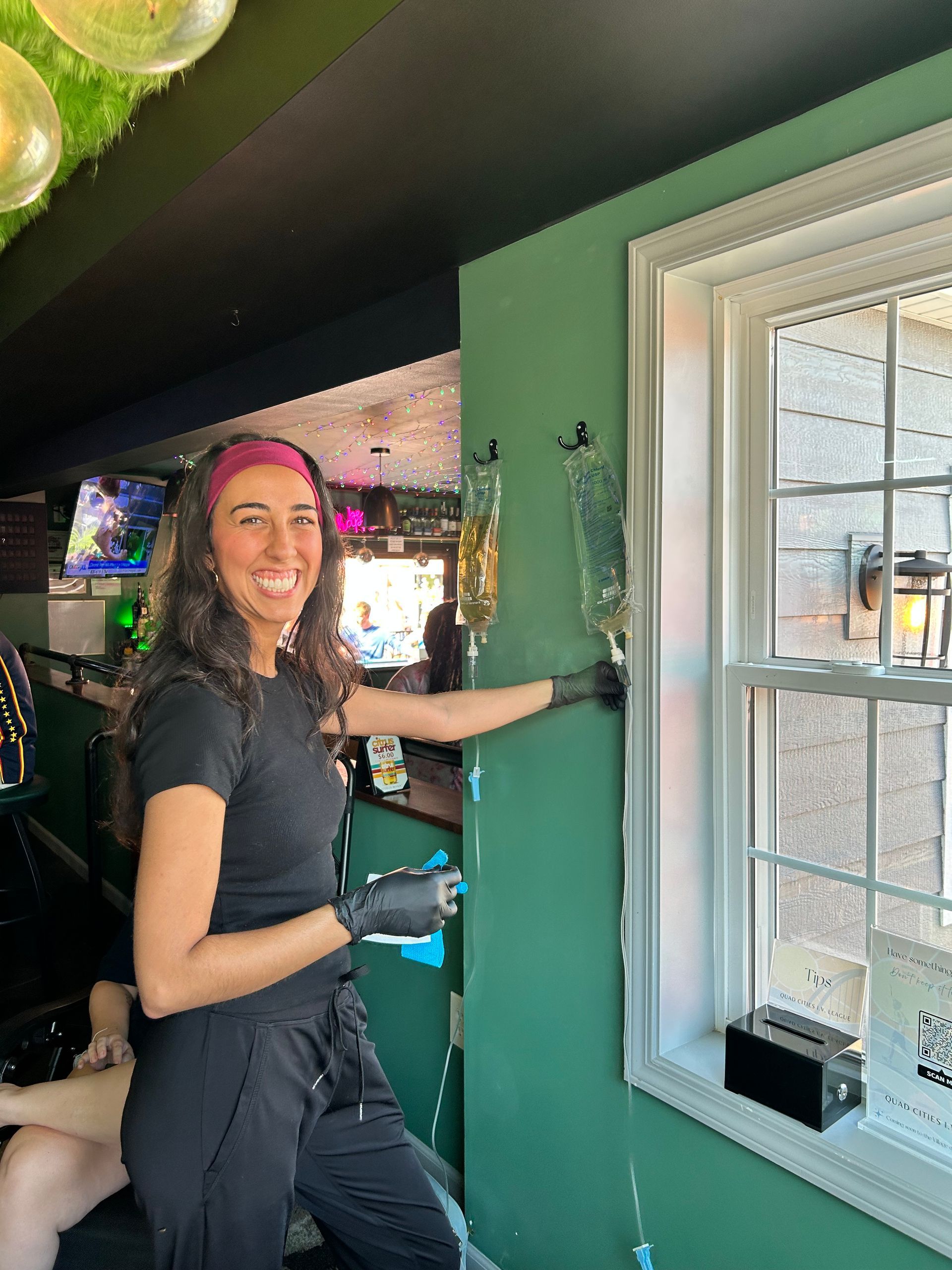 Two smiling people at an outdoor picnic table under a canopy, with colorful tables and grass in the background