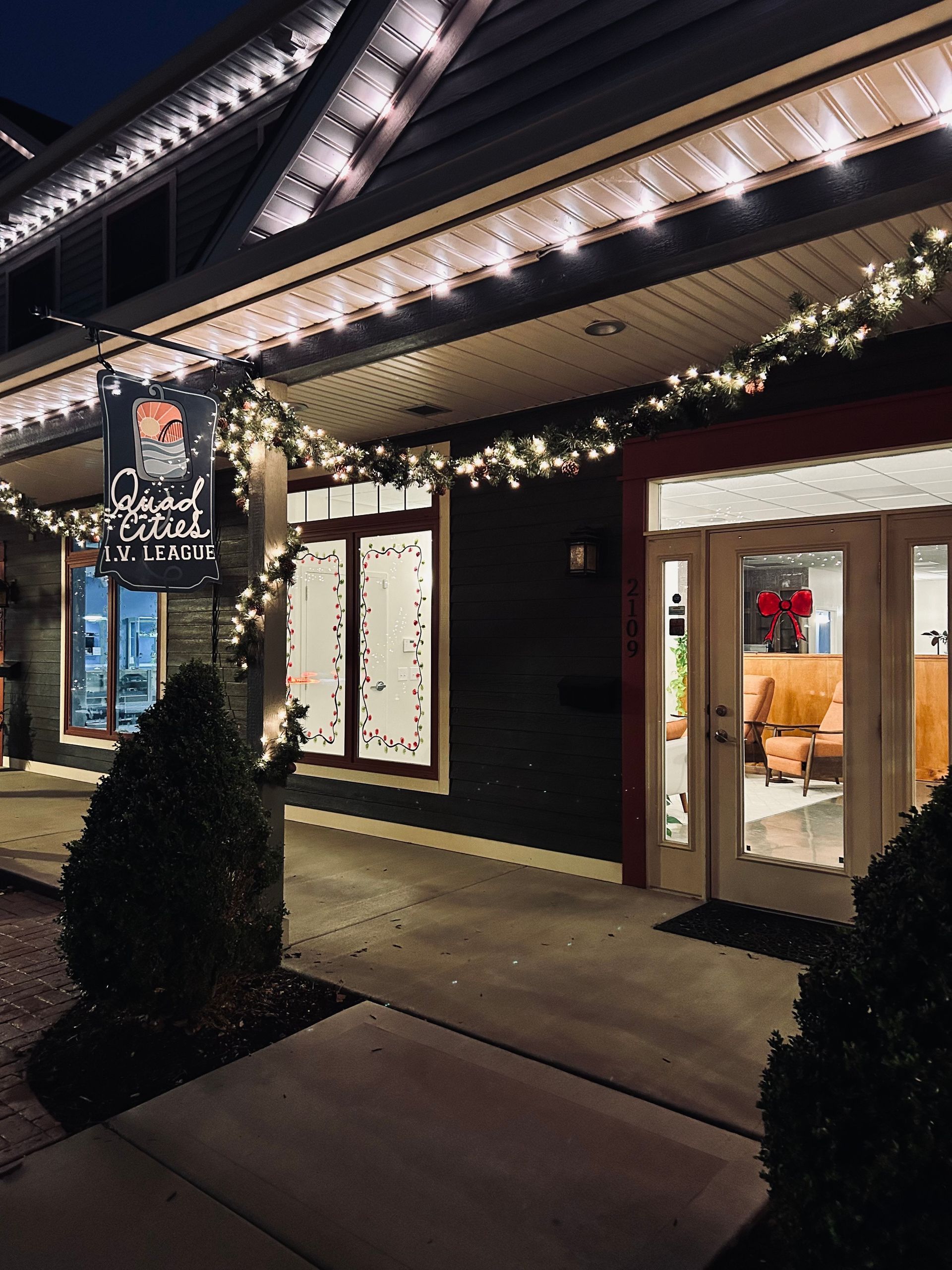 Nighttime exterior of Quad City I.V. League with string lights and a hanging sign.